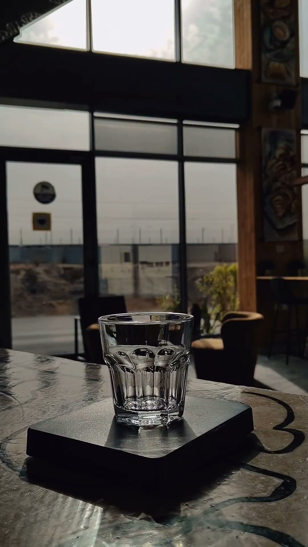 Macro pour of a dark drink into a glass on a black surface.